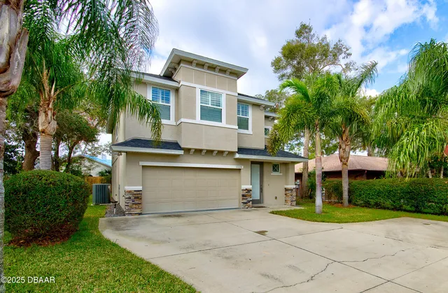 a view of a white house with a large tree and a yard in front of it
