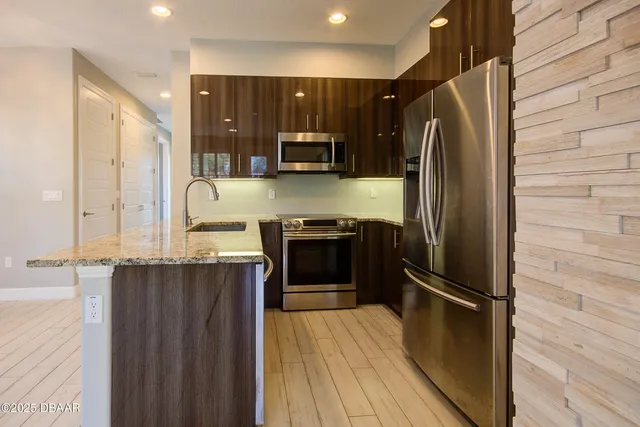 a kitchen with stainless steel appliances granite countertop a refrigerator and a stove top oven