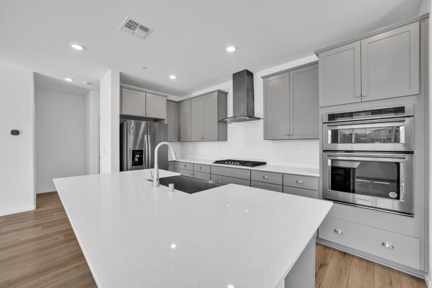 4562 Butterfly Ridge Drive Folsom, CA 95630 - Photo 9 of 44 a kitchen with stainless steel appliances a stove a sink a refrigerator white cabinets and wooden floor