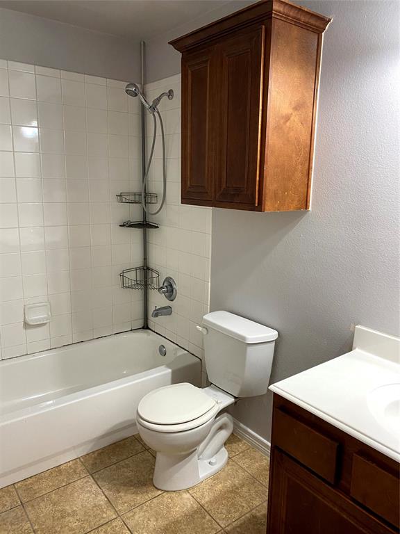 906 Parkplace Ridge Princeton, TX 75407 - Photo 3 of 31 Bathroom featuring a white bathtub with subway tile surround, tile flooring, a white toilet, a wood-finish vanity with a white countertop, and a wood-finish wall-mounted cabinet
