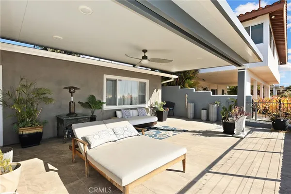 a view of a patio with couches table potted plants and floor to ceiling window