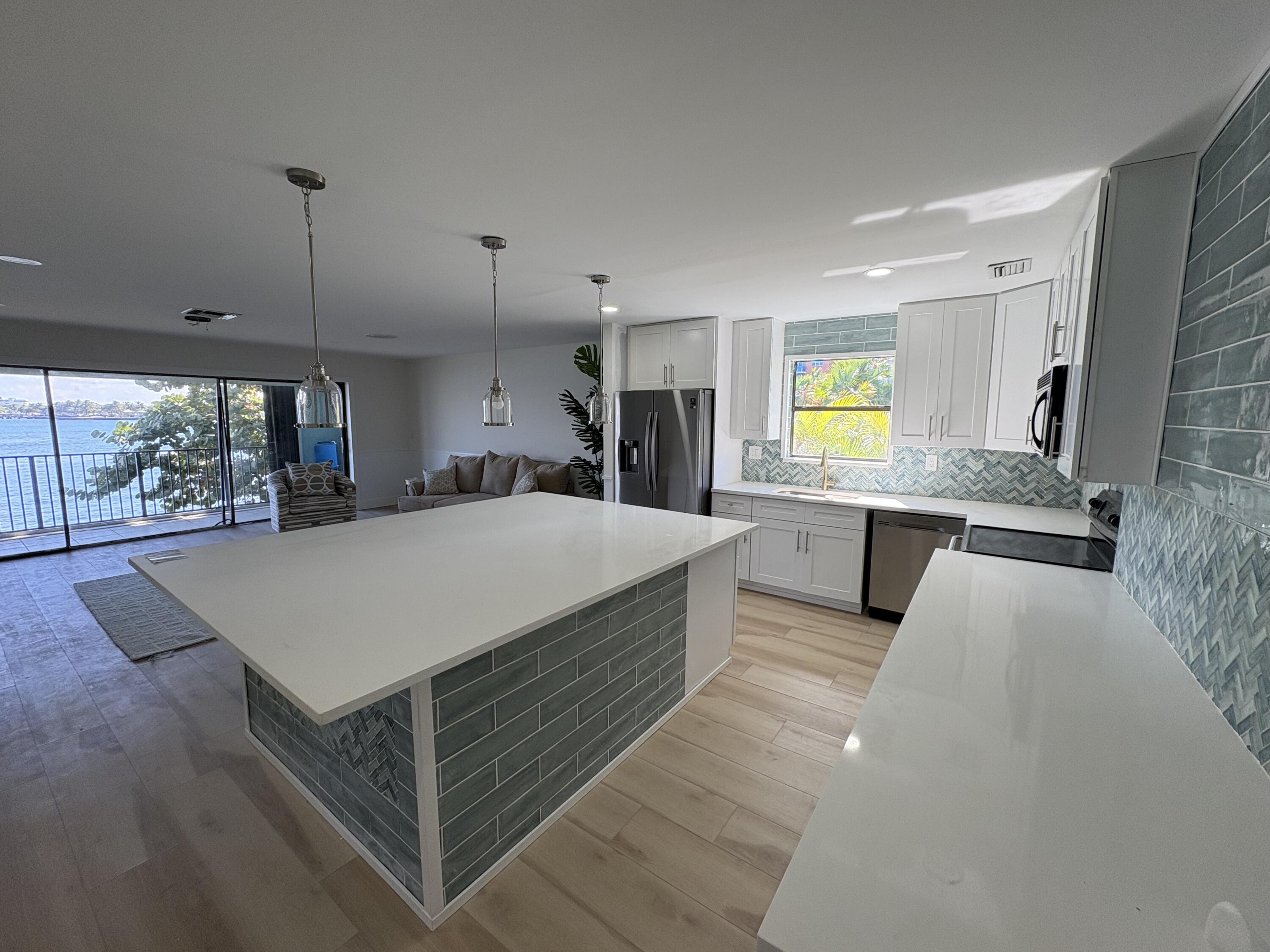 360 Wilma Circle, Unit 7 Riviera Beach, FL 33404 - Photo 6 of 15 a large kitchen with kitchen island a large counter space a sink a window and stainless steel appliances