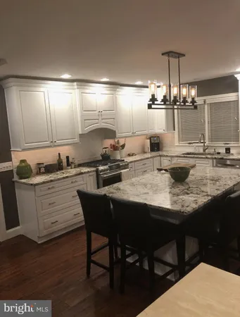 a kitchen with kitchen island granite countertop a sink cabinets and wooden floor
