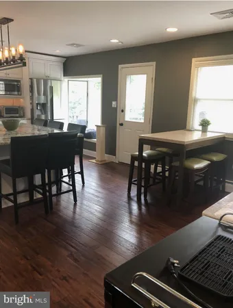 a kitchen with stainless steel appliances granite countertop a stove top oven a dining table and chairs with wooden floor