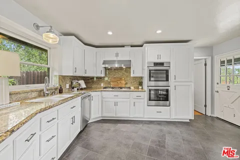a kitchen with granite countertop white cabinets and white appliances