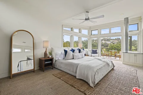 a bedroom with a bed and large windows