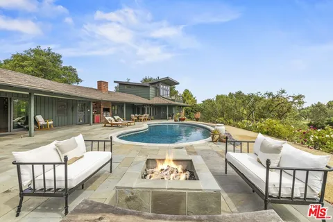 a view of a patio with couches table and chairs with wooden floor and fence