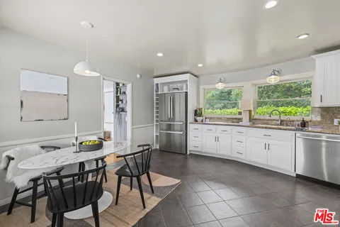 a kitchen with stainless steel appliances kitchen island granite countertop a stove a refrigerator and a dining table