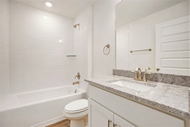 a bathroom with a granite countertop sink a toilet and bathtub
