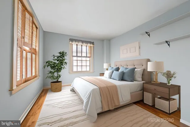 a bedroom with a large bed windows and wooden floor