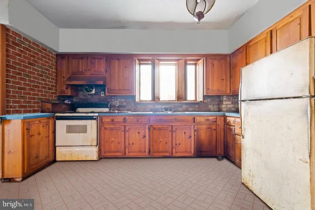 a kitchen with granite countertop a refrigerator a sink and white cabinets