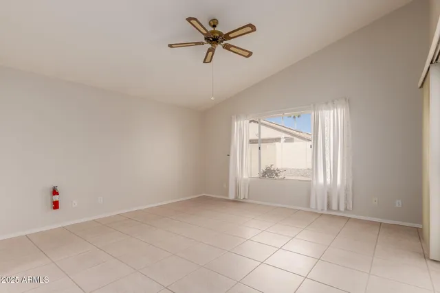 an empty room with chandelier fan and windows