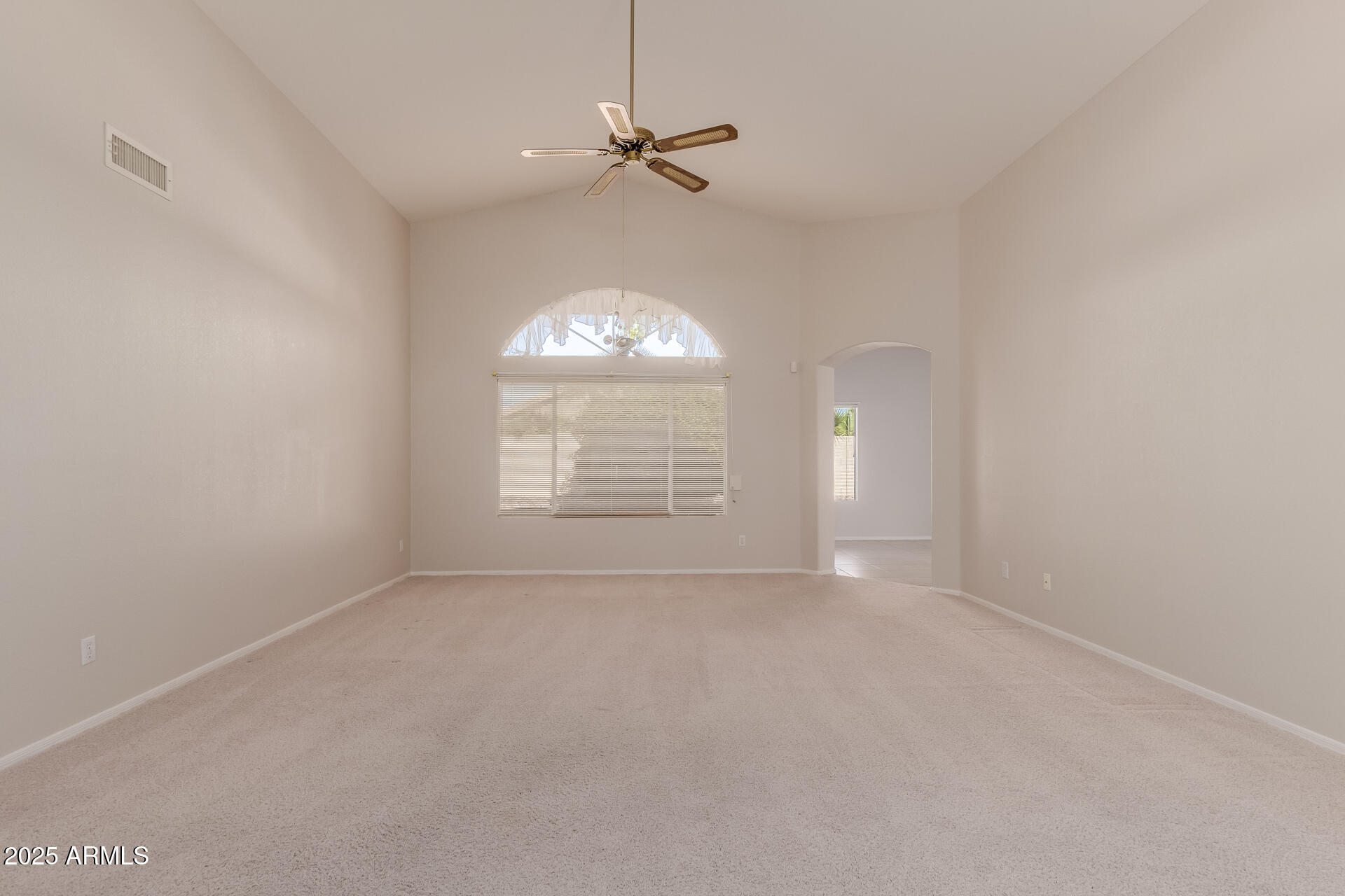 14588 West Bison Path Surprise, AZ 85374 - Photo 9 of 42 an empty room with a chandelier fan and windows