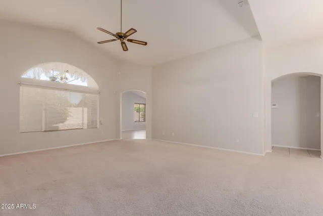 an empty room with a chandelier fan and windows