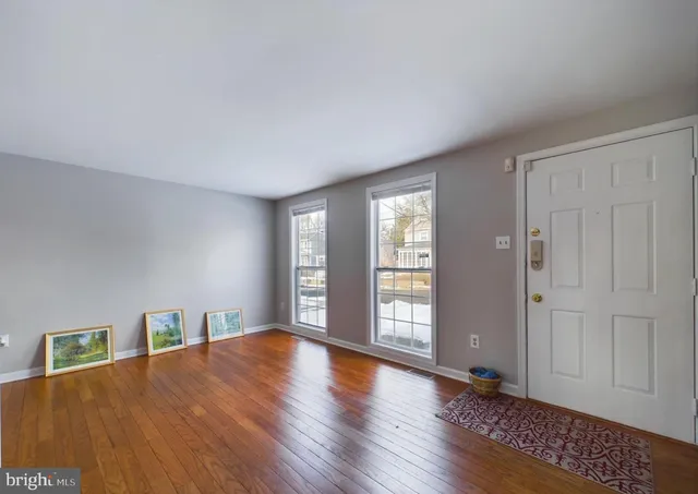 a view of an empty room with window and wooden floor