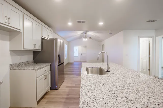 a kitchen with stainless steel appliances granite countertop a refrigerator a stove and a sink