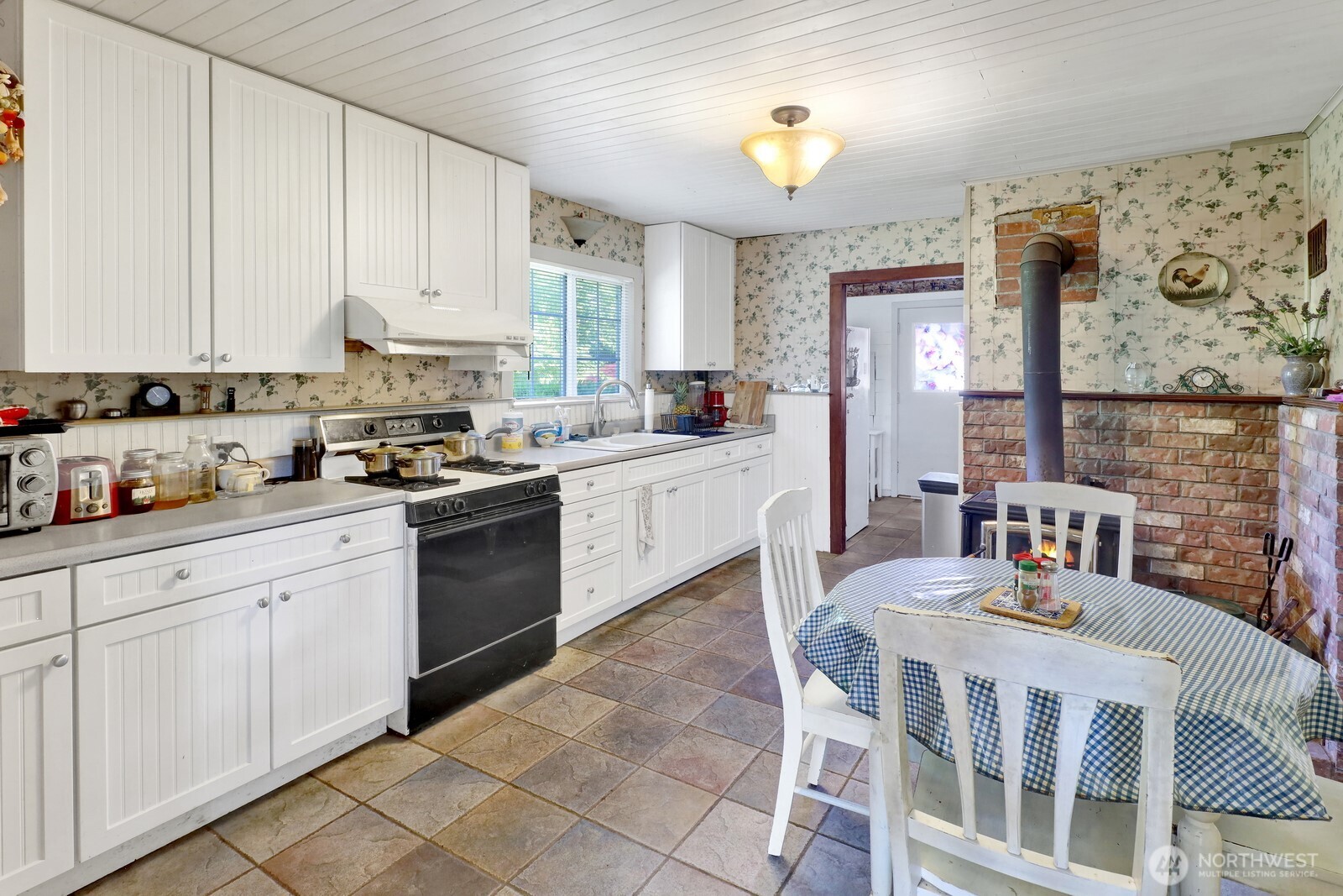 8172 Van Buren Road Everson, WA 98247 - Photo 9 of 33 a kitchen with stainless steel appliances granite countertop a stove top oven a sink a dining table and chairs with white cabinets