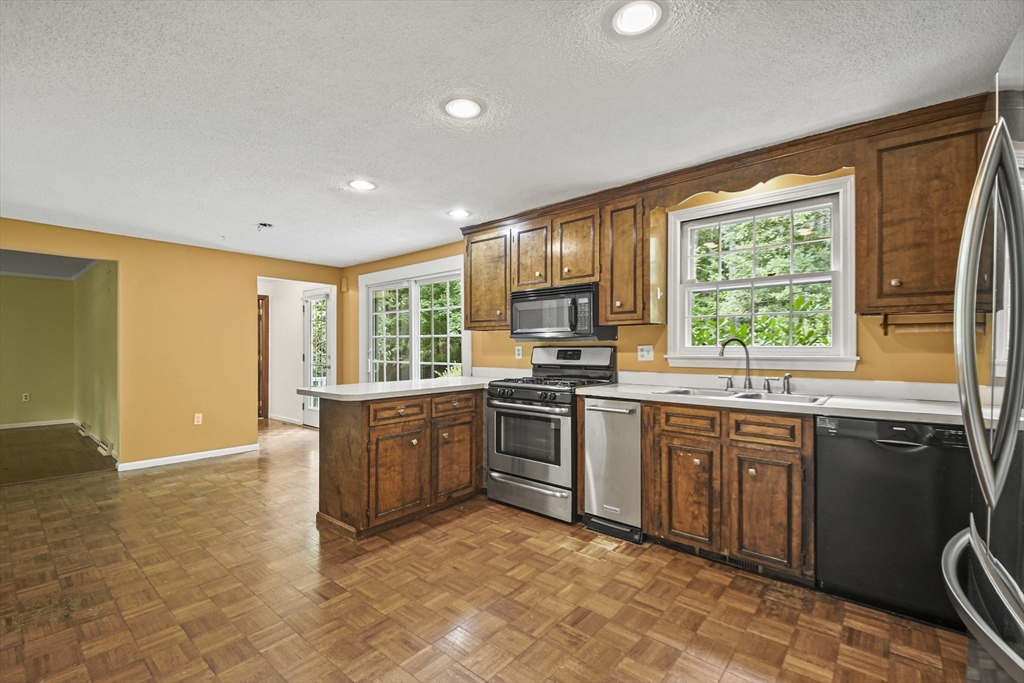 573 Main Street Dunstable, MA 01827 - Photo 9 of 42 a kitchen with stainless steel appliances granite countertop a stove a sink dishwasher a refrigerator and a dining table with wooden floor