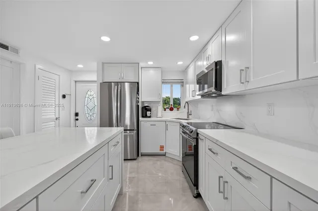 a kitchen with a sink a refrigerator and a stove top oven with white cabinets