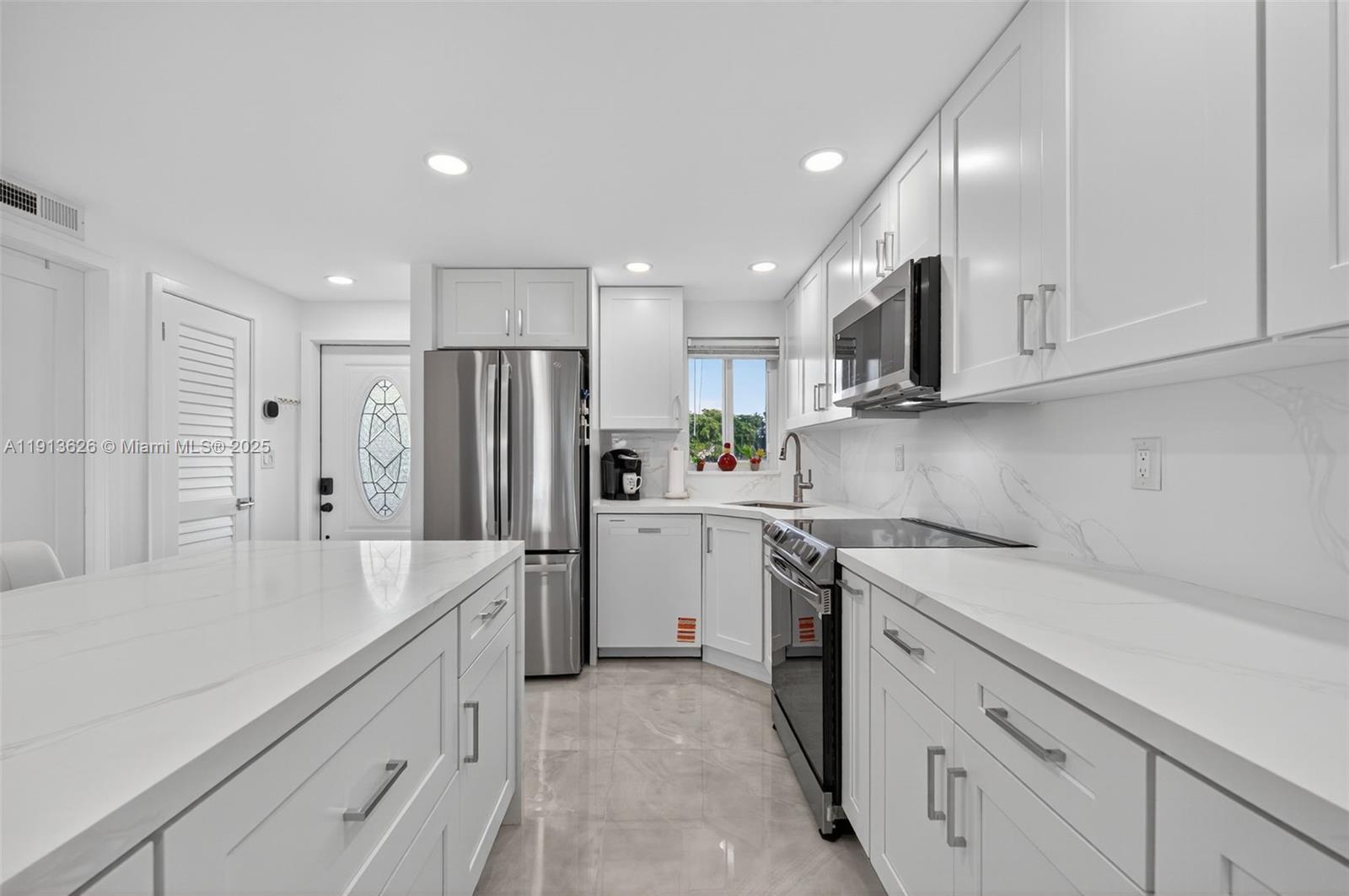 8900 Washington Street, Unit 410 Pembroke Pines, FL 33025 - Photo 4 of 79 a kitchen with a sink a refrigerator and a stove top oven with white cabinets