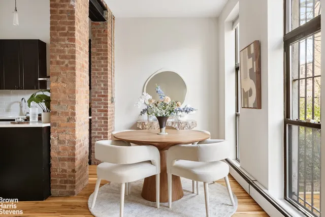 a dining room with stainless steel appliances granite countertop a refrigerator a stove top oven a dining table and chairs with wooden floor