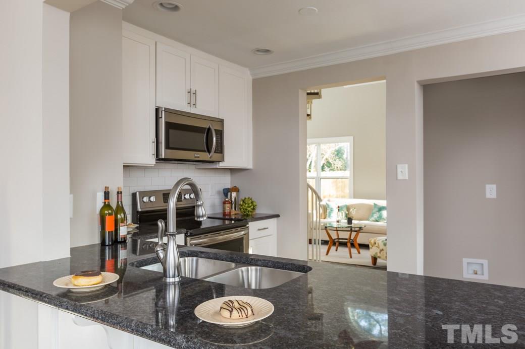 820 Colleton Road Raleigh, NC 27610 - Photo 9 of 25 a kitchen with granite countertop a stove a sink a dining table and chairs with wooden floor