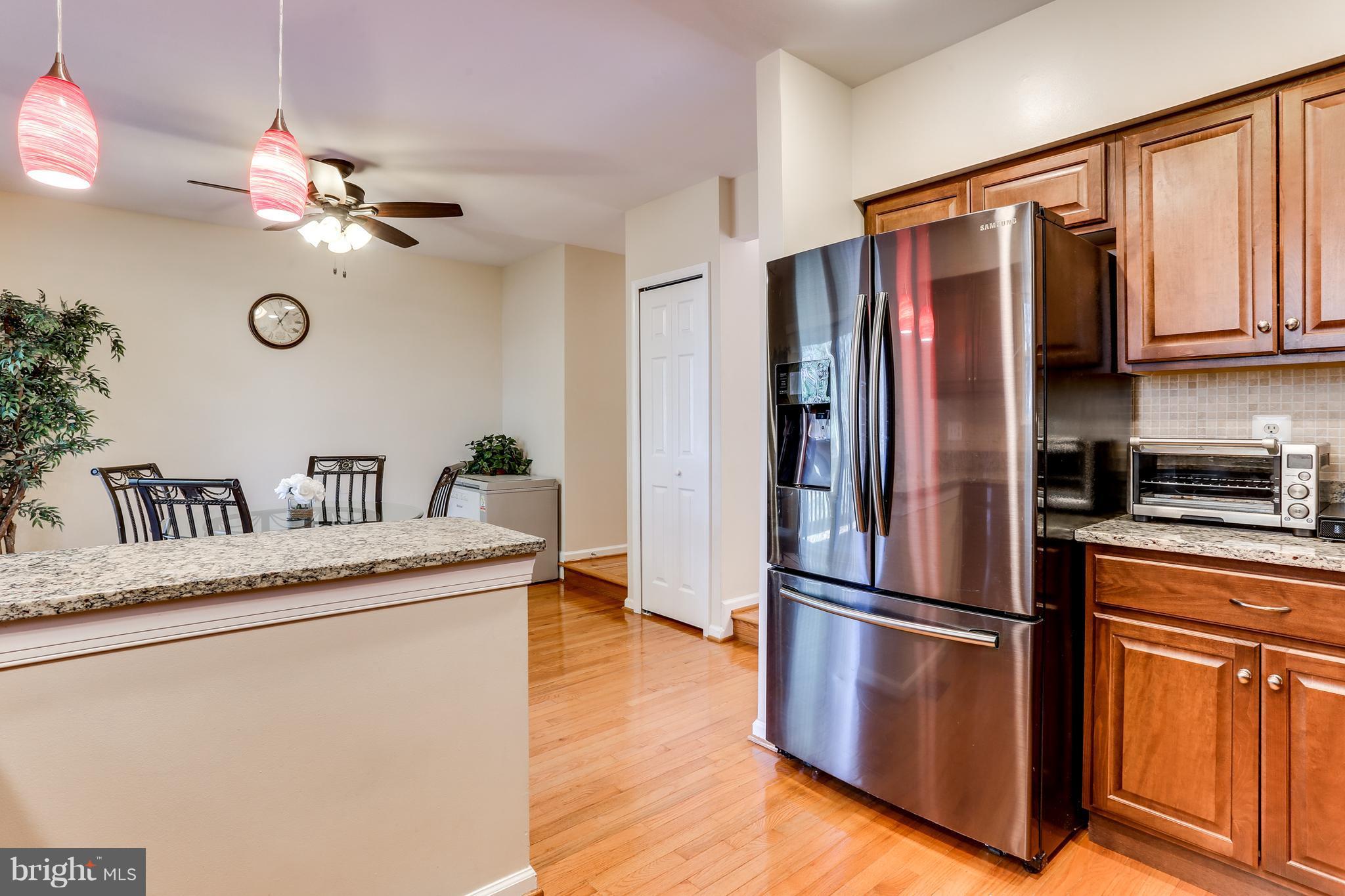 6141 Good Hunters Ride Columbia, MD 21045 - Photo 12 of 28 a kitchen with stainless steel appliances granite countertop a refrigerator a stove and a sink with wooden floors
