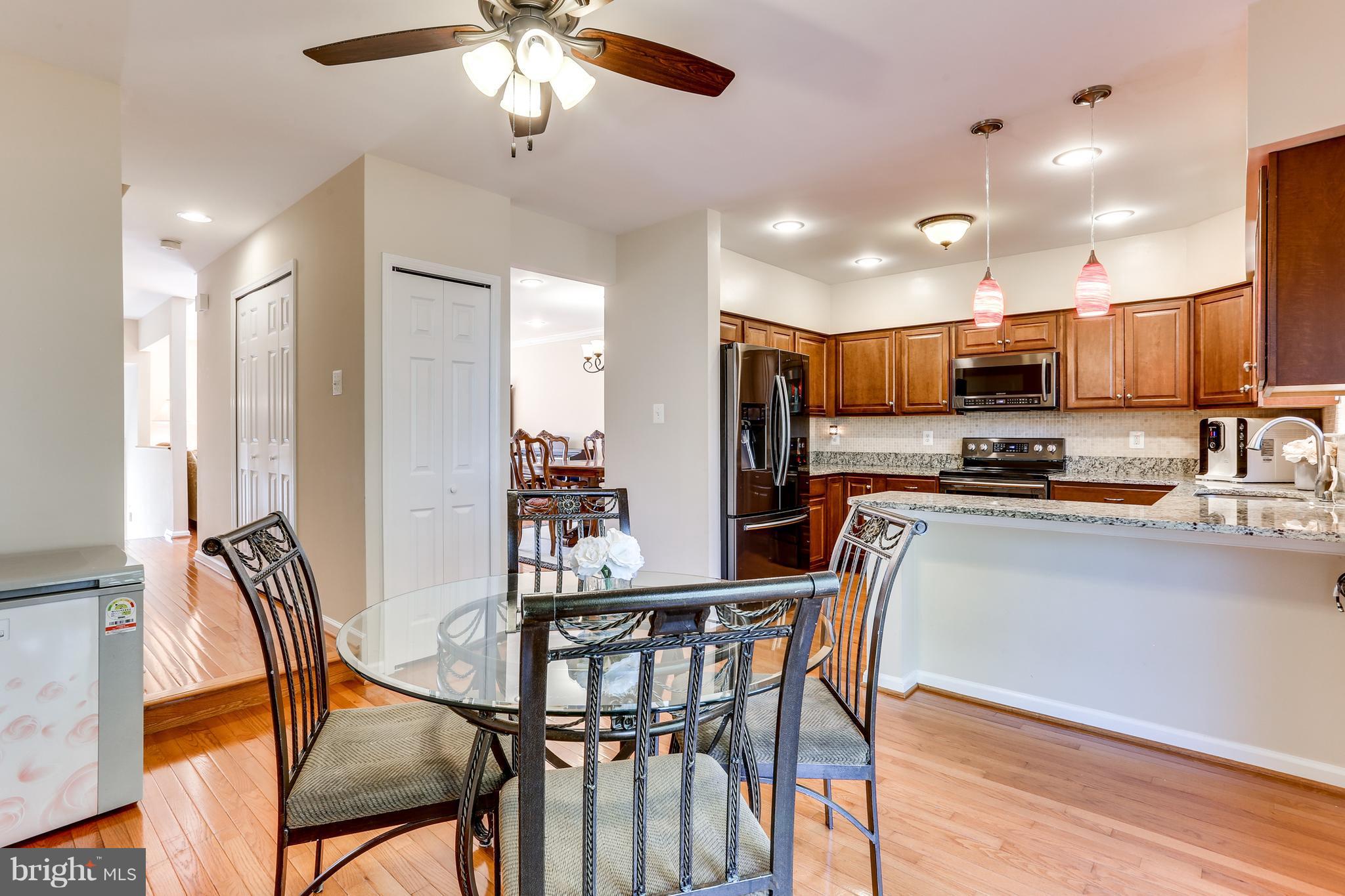 6141 Good Hunters Ride Columbia, MD 21045 - Photo 8 of 28 a kitchen with stainless steel appliances kitchen island granite countertop a dining table chairs and granite counter tops