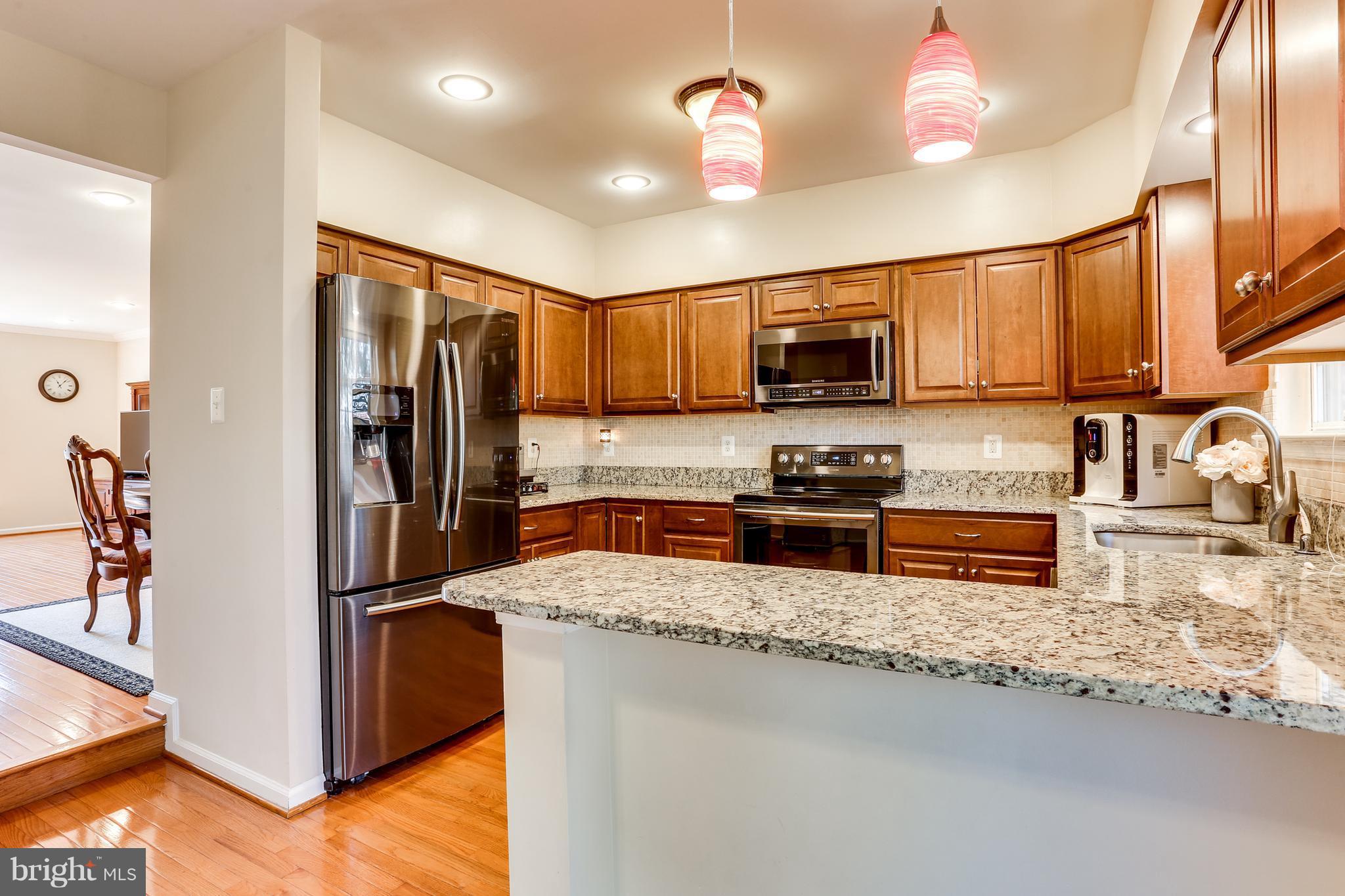 6141 Good Hunters Ride Columbia, MD 21045 - Photo 10 of 28 a kitchen with granite countertop a refrigerator and a stove top oven