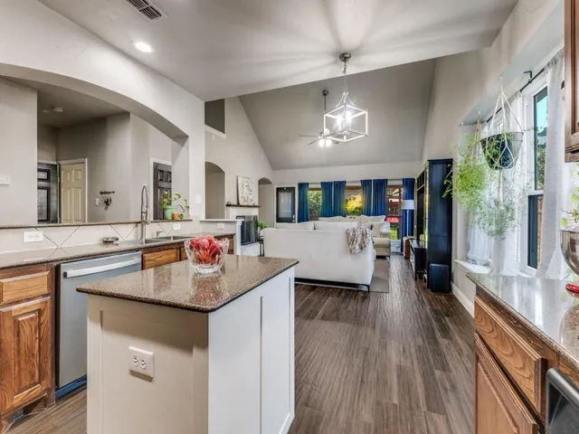 a kitchen with a sink dishwasher a stove and a dining table with wooden floor