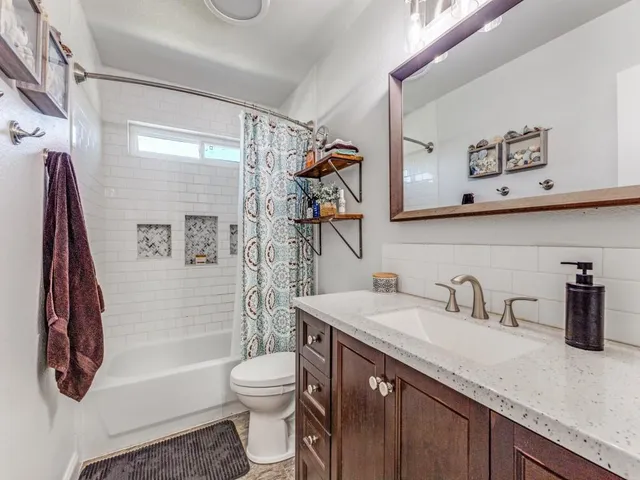 a bathroom with a granite countertop sink a toilet and shower