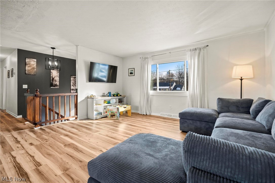 Living room featuring wood finished floors, a textured ceiling, and hanging lights
