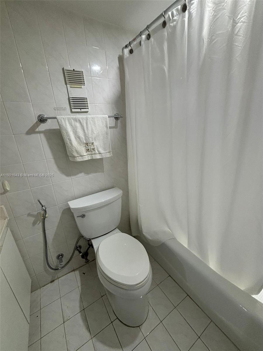 9431 Southwest 4th Street, Unit 201 Miami, FL 33174 - Photo 4 of 6 a white toilet sitting next to a shower curtain