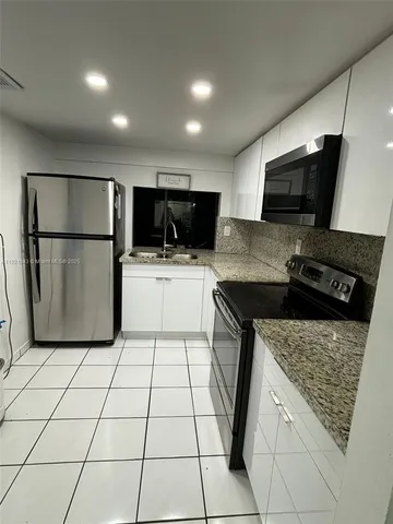 a kitchen with a sink a microwave a refrigerator and cabinets