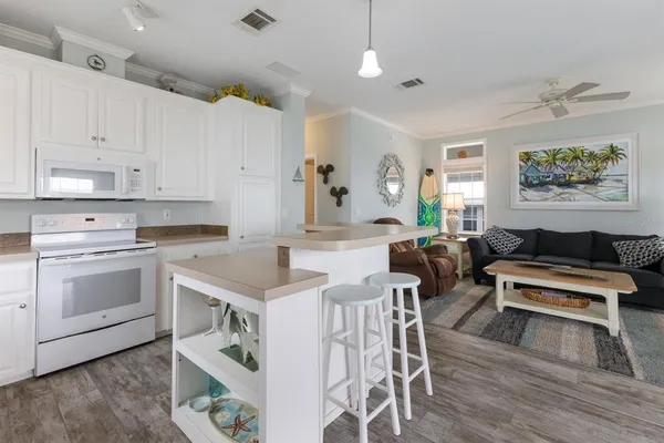 a open kitchen with stainless steel appliances granite countertop a stove top oven a refrigerator a sink and white cabinets with wooden floor