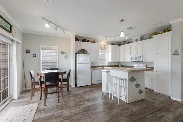 a kitchen with kitchen island granite countertop wooden floors and white cabinets