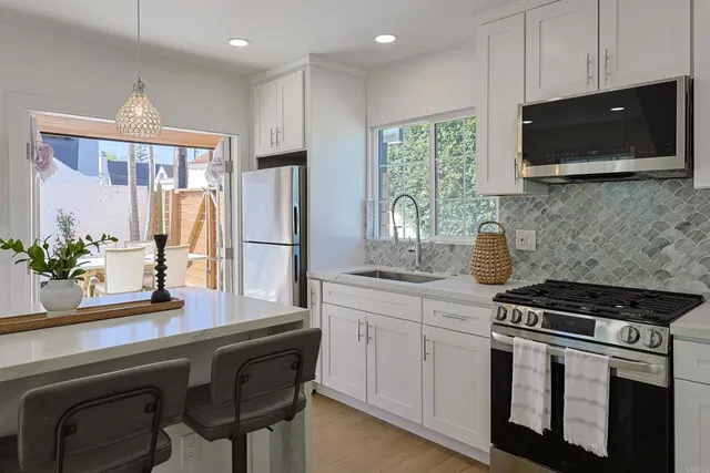 a kitchen with stainless steel appliances a sink a stove a microwave a refrigerator a stove and cabinets