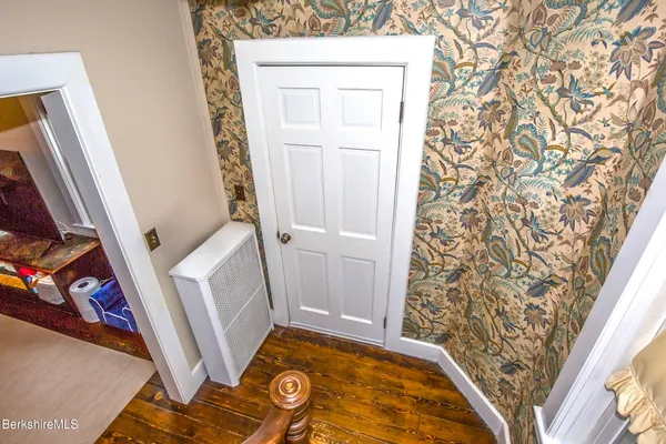 a bedroom with a bed a dresser and wooden floor