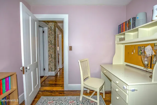 a view of a hallway with wooden floor and a bathroom