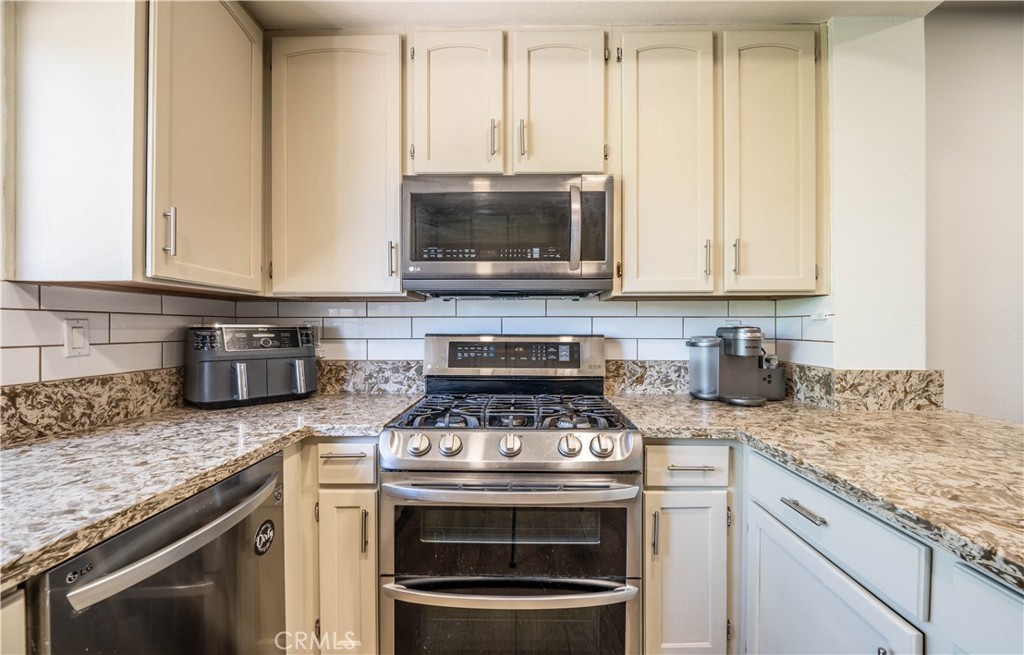 102 Vía Contento Rancho Santa Margarita, CA 92688 - Photo 5 of 40 a kitchen with granite countertop a stove top oven microwave and cabinets