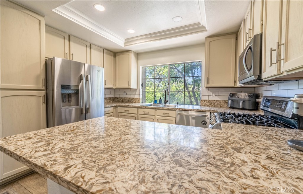 102 Vía Contento Rancho Santa Margarita, CA 92688 - Photo 6 of 40 a kitchen with stainless steel appliances granite countertop a refrigerator sink and cabinets