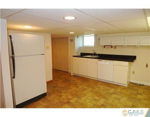 541 Georges Road Dayton, NJ 08810 - Photo 16 of 24 a kitchen with granite countertop a refrigerator a sink and white cabinets
