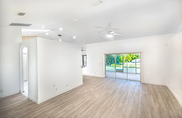 a view of an empty room with a window and wooden floor