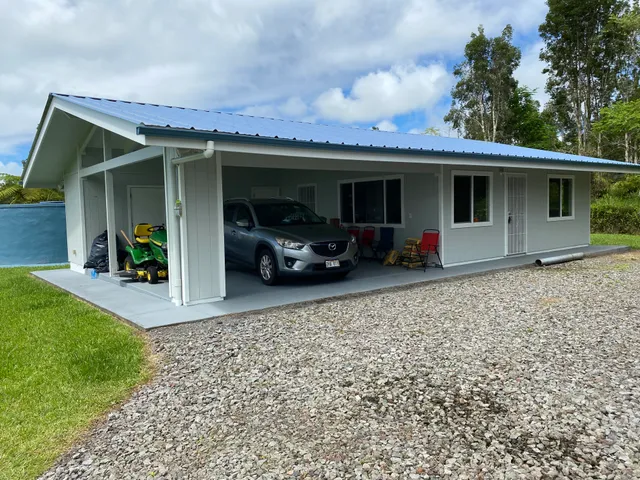 a view of a house with potted plants and a car parked in front of it