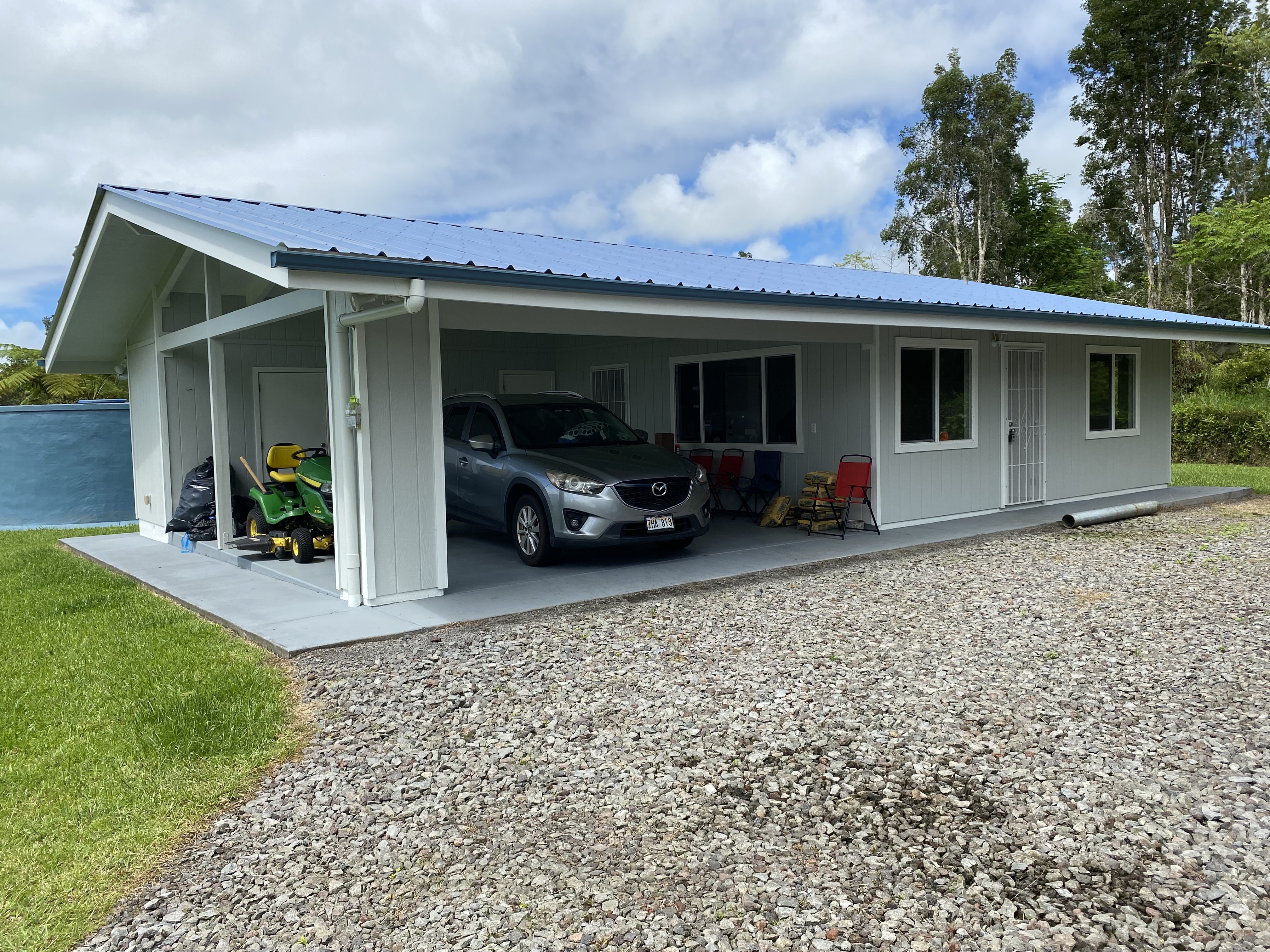 16-1321 Moho Road Keaau, HI 96749 - Photo 1 of 19 a view of a house with potted plants and a car parked in front of it