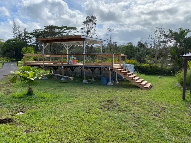 a view of a swimming pool and lounge chairs in back yard of the house