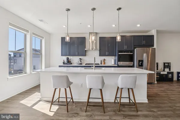 a kitchen with stainless steel appliances granite countertop a table chairs refrigerator and sink