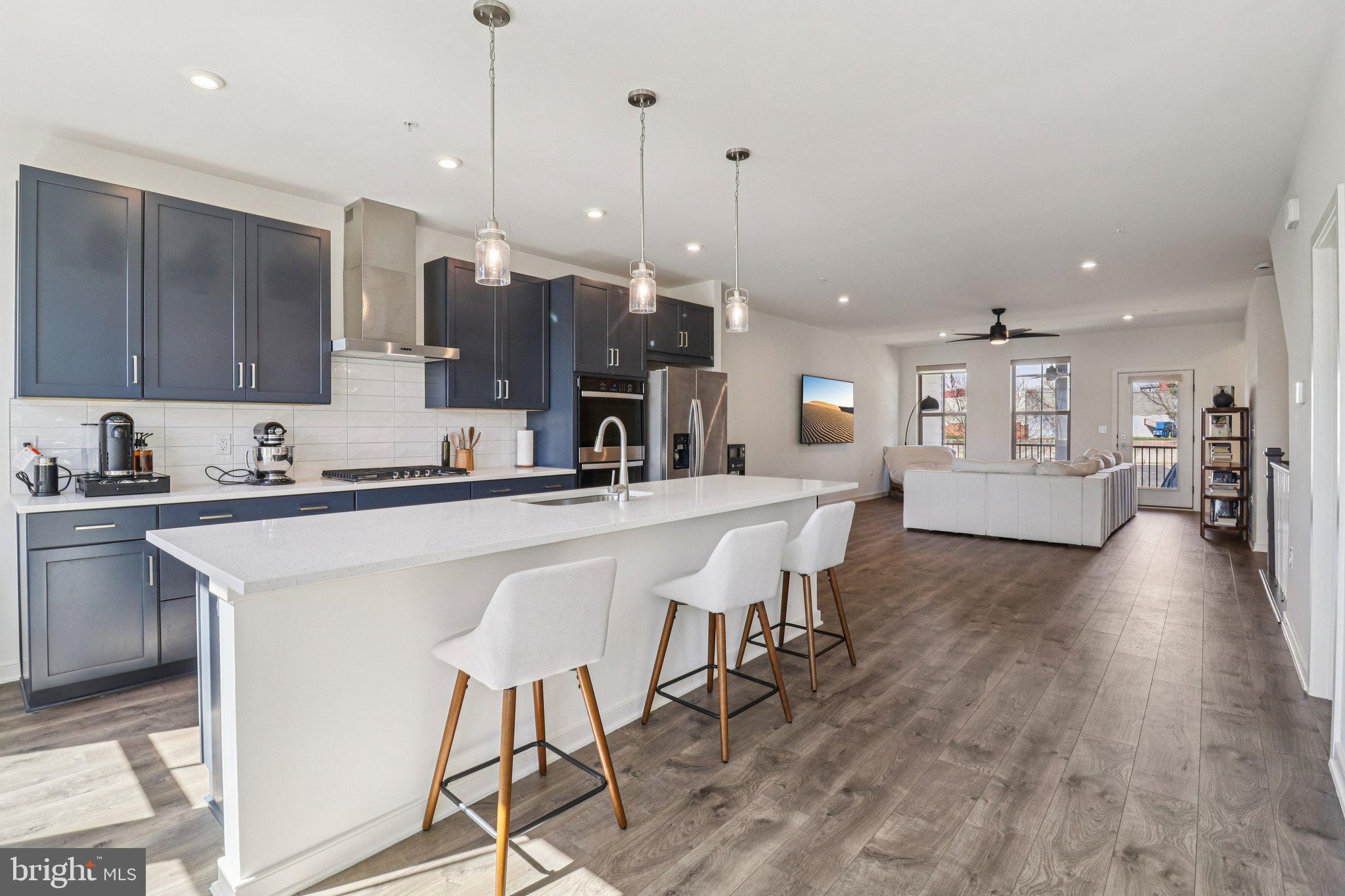 45916 Swallow Terrace Sterling, VA 20165 - Photo 5 of 41 a kitchen with stainless steel appliances kitchen island granite countertop a stove a sink a refrigerator and chairs with wooden floor