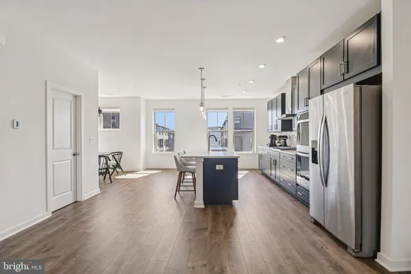 a kitchen with stainless steel appliances granite countertop a refrigerator a sink dishwasher a stove and white cabinets with wooden floor
