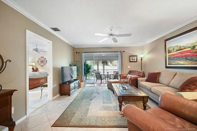 a living room with furniture two large window and a flat screen tv